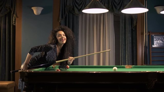 Beautiful woman in black dress play billiard