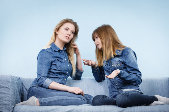 Two serious women friends talking on sofa