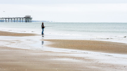 Man with fishing pole fishing on beach