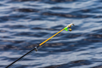 A beautiful rod with a bell on a background of lake