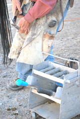 Cowboy farrier working on a horseshoe on the ranch.