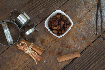 Obraz na płótnie Canvas Raisins spilled from a bowl on the wooden table. Cinnamon, vanilla and powdered sugar
