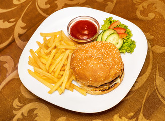 Plate with hamburger, french fries and sauce on the table at the bar. Top view.