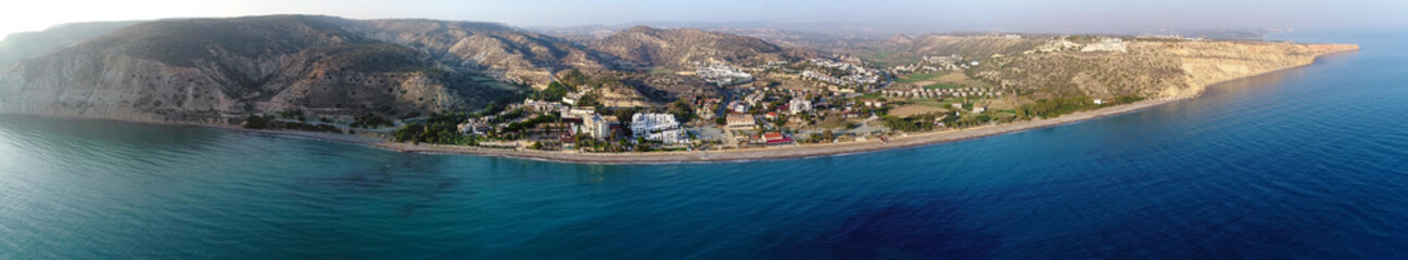 Fototapeta na wymiar Aerial panoramic view of Pissouri bay, a village settlement between Limassol and Paphos in Cyprus. View of the coastline panorama, beach, hotel, resort, hills, plain and building developments.