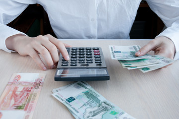 The girl at the table considers the profit with the calculator