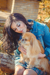 Young woman in denim jacket dressed in the casual style at nature in the countryside for a spring or autumn walk with a light red dog. Pet owner in village on a rest 