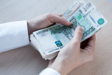Female hands hold many large bills of Russian money
