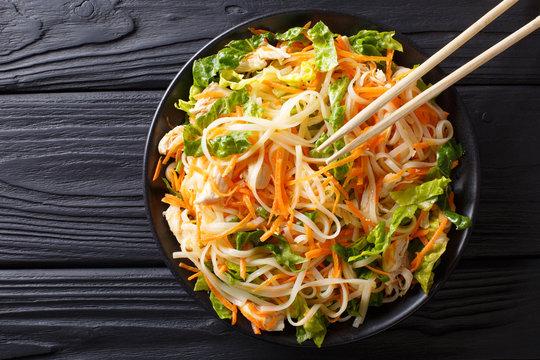 Vietnamese chicken salad with rice noodles, carrots and herbs macro. horizontal top view