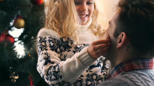 Cropped view of little daughter hugging and playing with her father near the christmas tree at home

