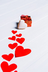 Stitch of red hearts gingerbread and a gift on a white background of wood texture. Valentine's Day