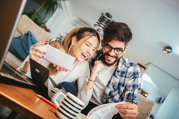 Woman and man doing paperwork together, paying taxes online on notebook pc