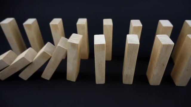 VIDEO two lines of dominoes falling in sequences on dark background in slow motion
