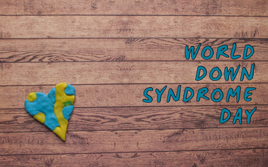 Fototapeta na wymiar World Down syndrome day with blue yellow awareness heart on dark wooden background.