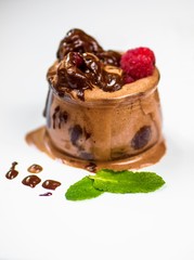 Glass with whipped cream and raspberry in chocolate topping.