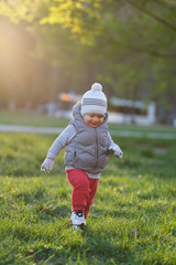 Toddler child in warm vest jacket outdoors. Baby boy at park.