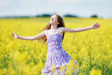 Naklejka na ściany i meble joyful girl with flower garland at yellow rape seed meadow