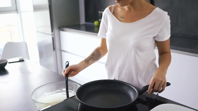 Cropped view of a calm asian woman standing by the stove on kitchen and cooking pancakes