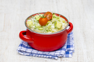 Red saucepan with okroshka - traditional summer soup in Ukraine, Belarus and Russia. Close up