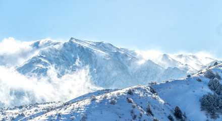 Fototapeta na wymiar Clouds on snow-capped mountains