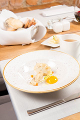 Broth with dumplings and an egg yolk being  served in a jug in a restaurant