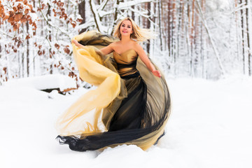 Young woman in a long dress in winter forest