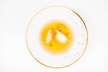 Dumplings in broth with an egg yolk on a white background
