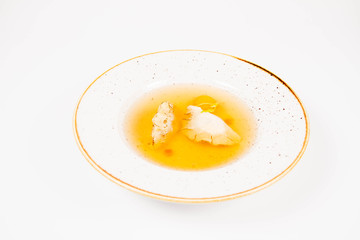 Dumplings in broth with an egg yolk on a white background