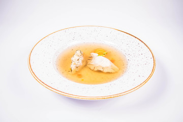 Dumplings in broth with an egg yolk on a white background