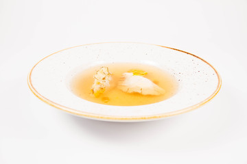 Dumplings in broth with an egg yolk on a white background