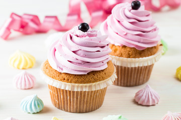 Closeup of cupcakes with vanilla, berries, pink and white cream, chocolate and sprinkles on wooden background. Selective focus. Sweet dessert tasty food concept muffin.