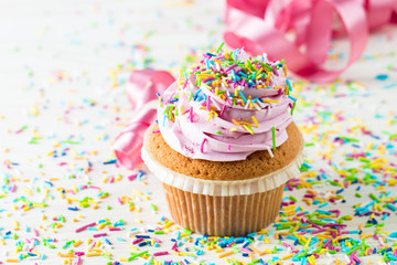 Closeup of cupcakes with vanilla, berries, pink and white cream, chocolate and sprinkles on wooden...