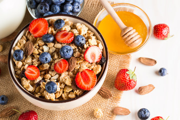 Healthy breakfast concept with oat flakes and fresh berries on rustic background. Food made of granola, muesli. Healthy banana smoothie with blackberries, muslie, strawberries, blueberries and honey.