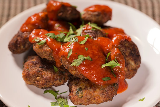 Close up of fried meatballs made from pork and beef meat with tomato sauce and herbs