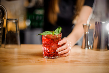 barmaid holds a crystal glass with a cocktail of red color