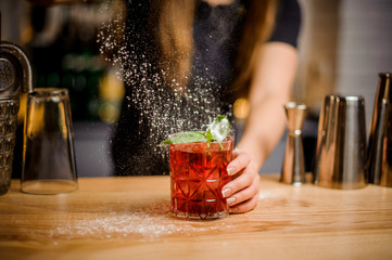 blondy barmaid finishes preparation of cocktail by adding a bitter of powdered sugar - obrazy, fototapety, plakaty