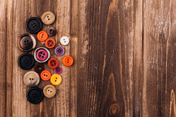 Fototapeta premium Colorful buttons for handicraft lie on wooden table