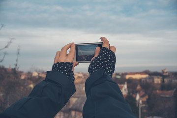Girl with the phone takes pictures of the city's panorama