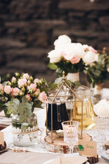 Little dinner table served in rustic style and decorated with pink flowers stands outside