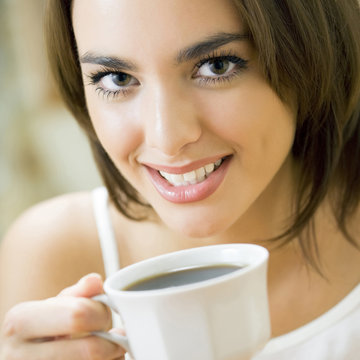 Young happy smiling woman drinking coffee, at home