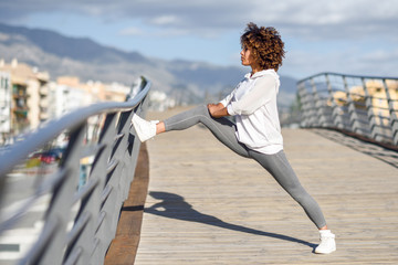 Young black woman doing stretching after running outdoors