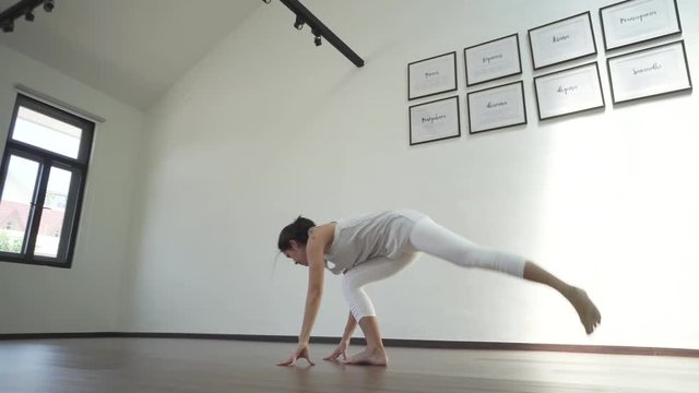 Asian chinese woman practising yoga in a generic white yoga studio