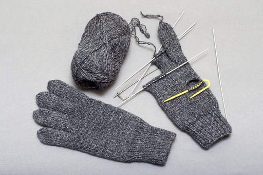 The process of knitting woolen gloves on knitting needles, pure wool, a warm winter accessory