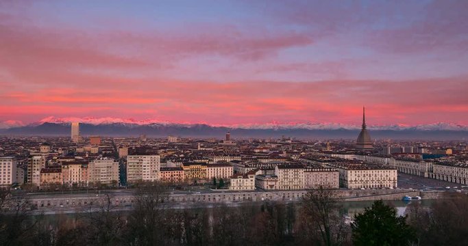 Turin Time lapse Italy, Torino skyline with the Mole Antonelliana towering over the buildings, sunrise with colorful sky glowing Alps in the background. 