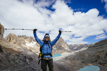 female mountaineer cheers on a 5000 meter high pass along the Huayhuash- Trek in the Peruvian...