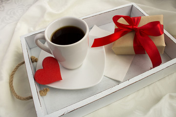 Coffee and gift box  on the white wooden tray in the bed