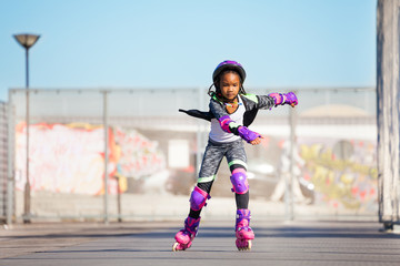 African girl rollerblading fast at skate park - obrazy, fototapety, plakaty