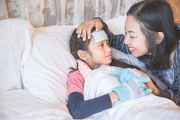 Asian mother take care sick daughter on bed