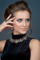 luxury jewelry and fashion concept. A model with earrings necklace and ring on gray background