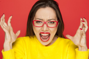beautiful angry woman with red glasses on red background