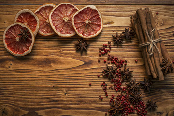 on a wooden table lay a ring of dried grapefruit,cinnamon,star anise